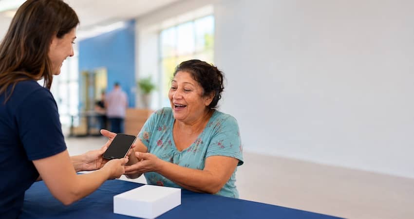 Woman receiving a free cell phone from a service representative with no deposit and no activation fee.