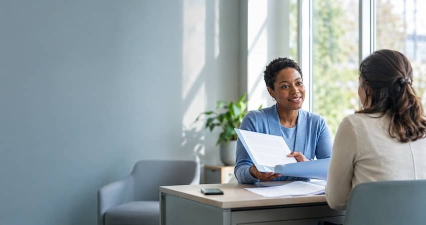 Two women reviewing paperwork while discussing whether the Lifeline Program is ending