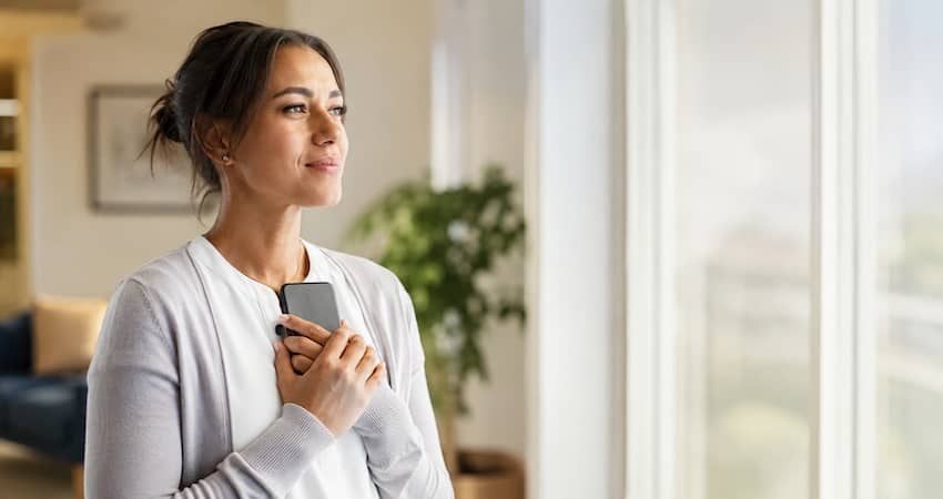 Woman holding a smartphone while seeking emergency Lifeline support under the Safe Connections Act